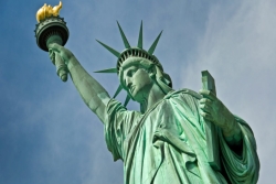 Closeup view from the bottom of the Statue of Liberty looking up against a blue sky background